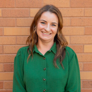 Erica smiles in front of a brick wall.