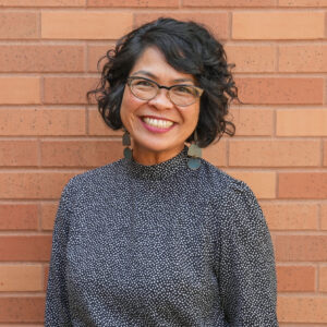 Rachel smiles in front of a brick wall.